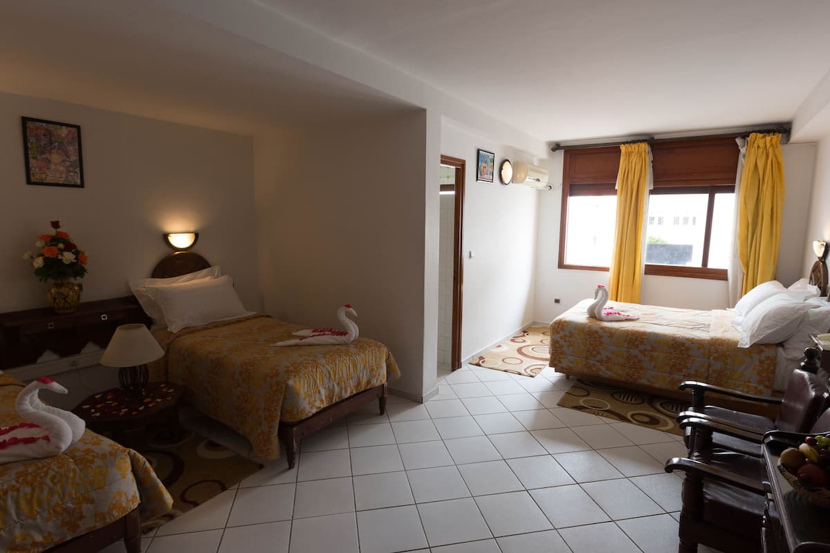 Habitación de hotel con dos camas, una zona de estar y una mesa de comedor.