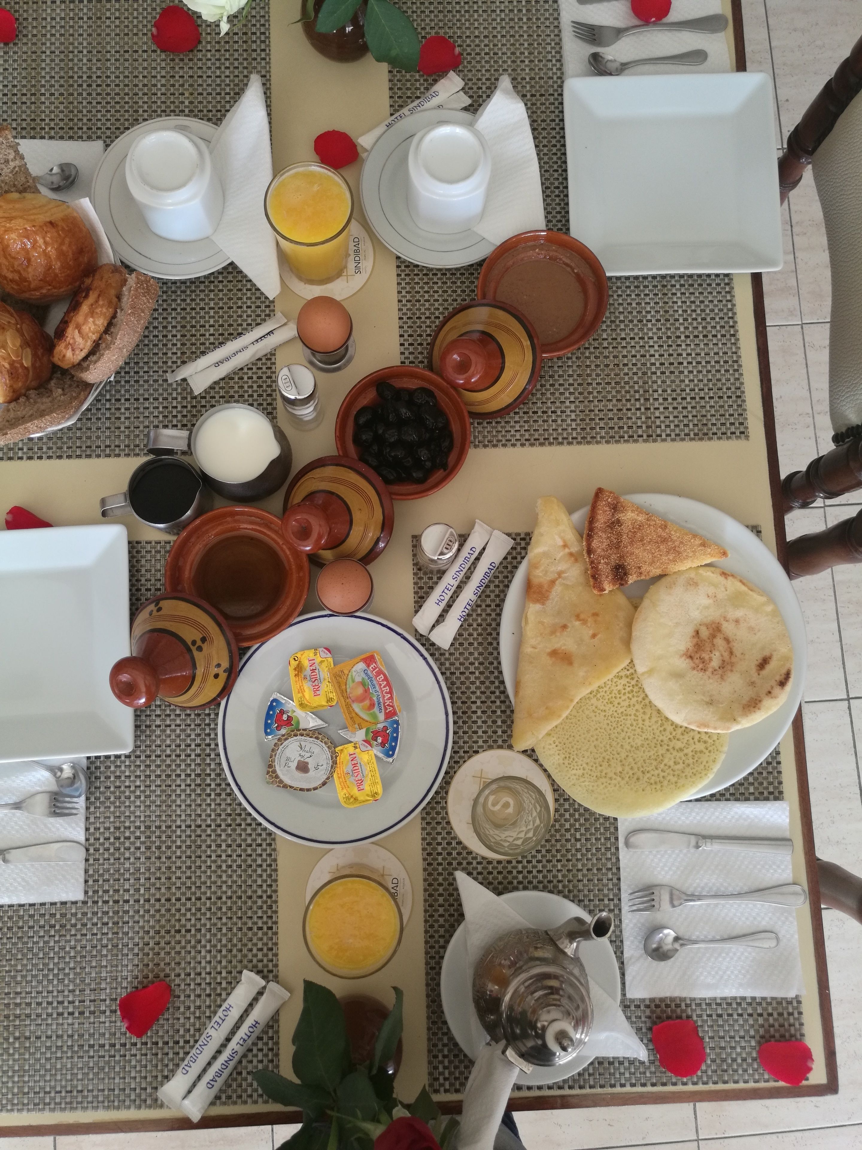 Una mesa de desayuno con diversas opciones de comida, incluyendo pan, bollería y un plato de huevos.