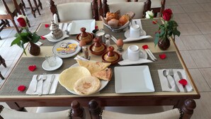 A dining table set with plates, cutlery, and a variety of food items including bread and pastries. - Hotel Sindibad (Agadir)