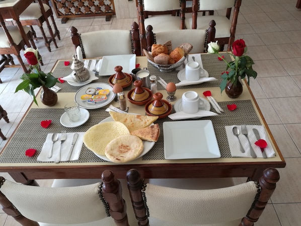A dining table set with plates, cutlery, and a variety of food items including bread and pastries. - Hotel Sindibad (Agadir)