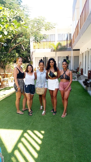 A group of people standing on a green lawn in a courtyard with a building in the background. - Dejavu Hotel (Gili Trawangan)