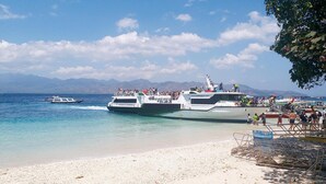 A beach with boats docked and people walking along the shore. - Dejavu Hotel (Gili Trawangan)