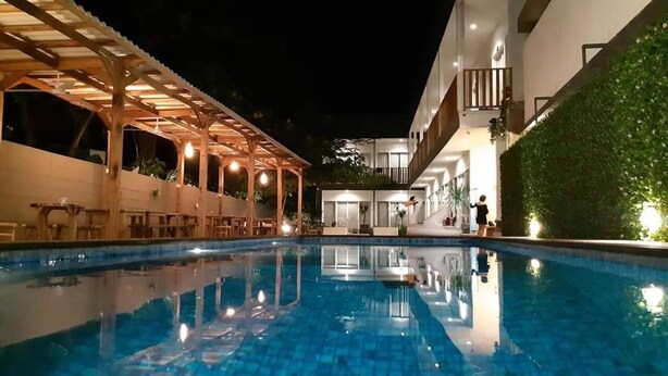 A swimming pool with a wooden pergola and a covered seating area. - Dejavu Hotel (Gili Trawangan)