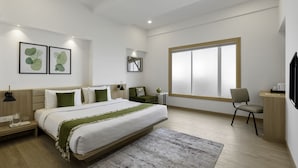 A modern hotel room with a large bed, bedside tables, a desk, and a large window. - Lemon Tree Hotel Vadodra (Vadodara)