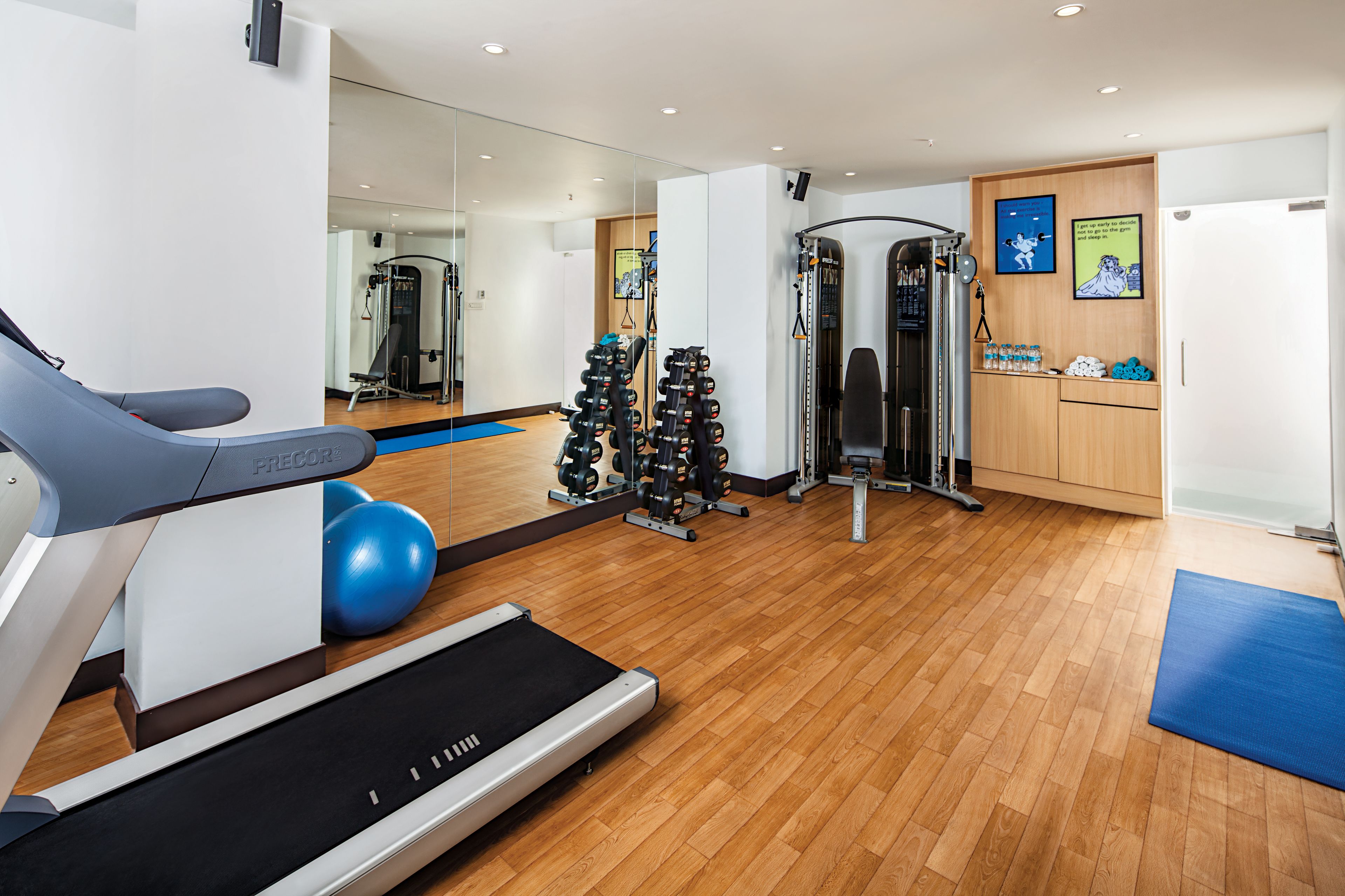 A gym with exercise equipment, a treadmill, and a mirrored wall.