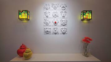 A wall with a grid of 12 head sculptures and two wall-mounted light fixtures.