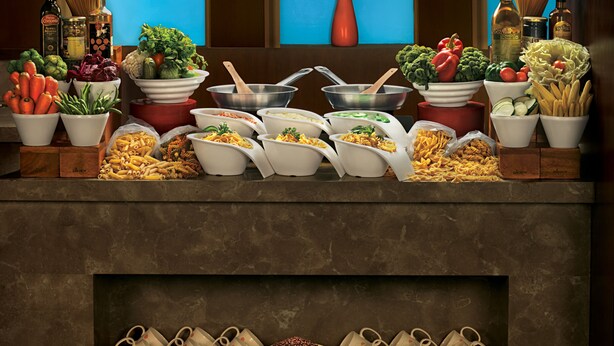 A buffet setup with various food items and utensils. - Lemon Tree Hotel Vadodra (Vadodara)