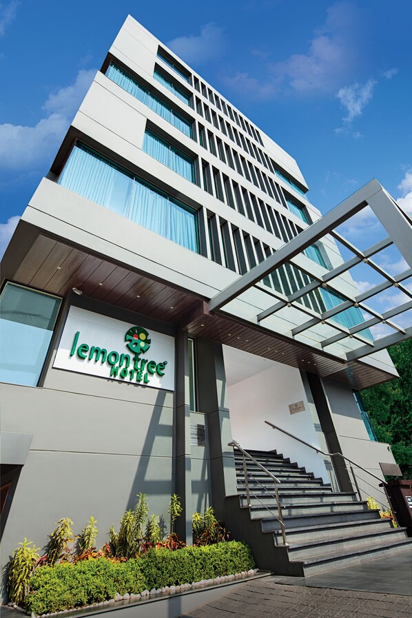 A modern hotel with a prominent sign, a covered entrance, and a staircase leading to the entrance.