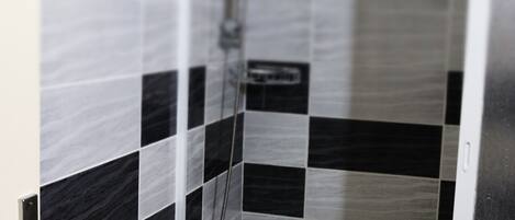 Un baño pequeño con ducha, inodoro y lavamanos.