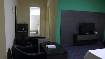 A hotel room with a bed, a desk with a chair, a television, and a mirror.