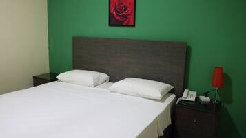 A neatly made bed with white linens, a grey headboard, and a red telephone on a bedside table.