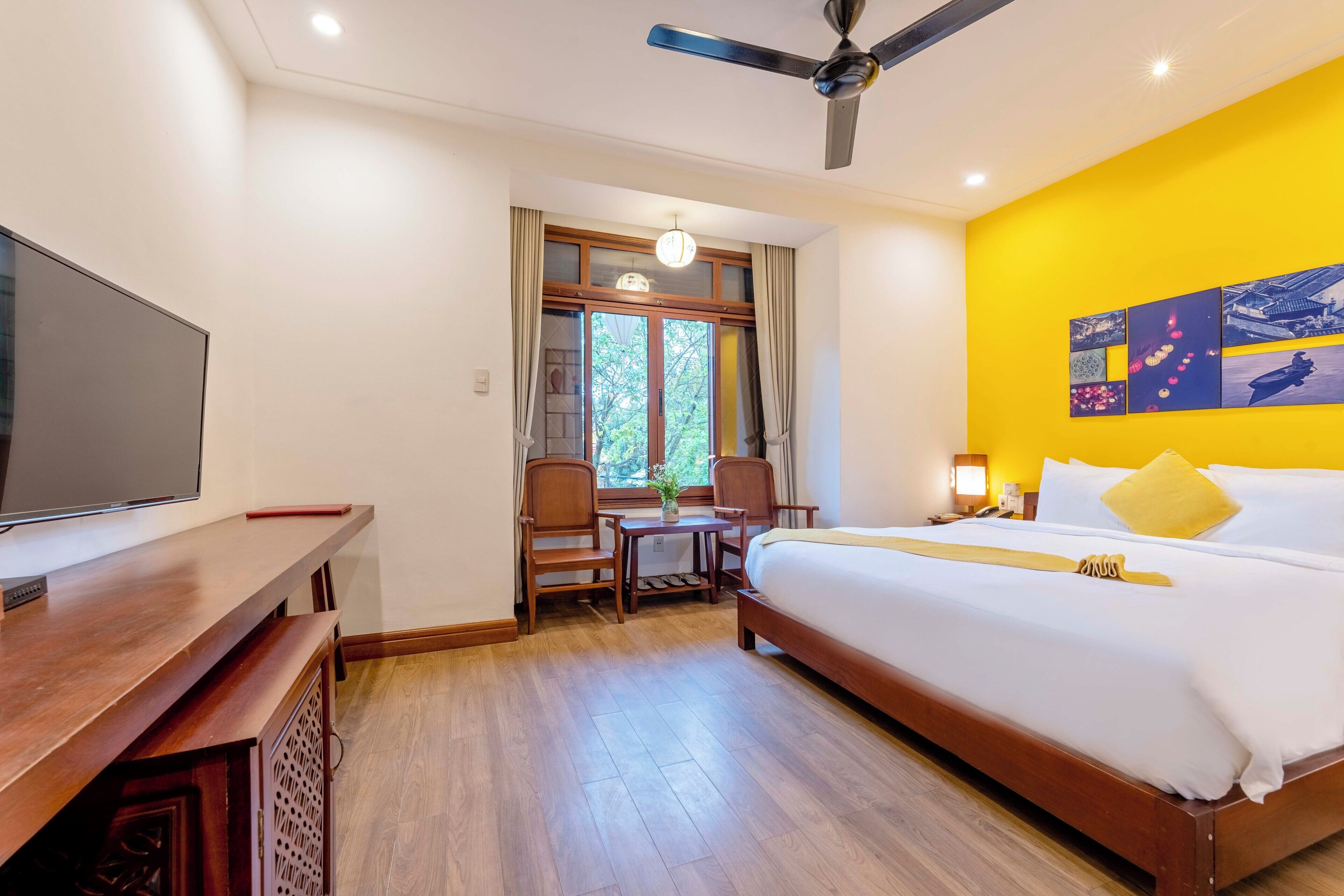 Une chambre d’hôtel équipée d’un lit, d’un bureau, d’une chaise, d’une télévision et d’un ventilateur de plafond.