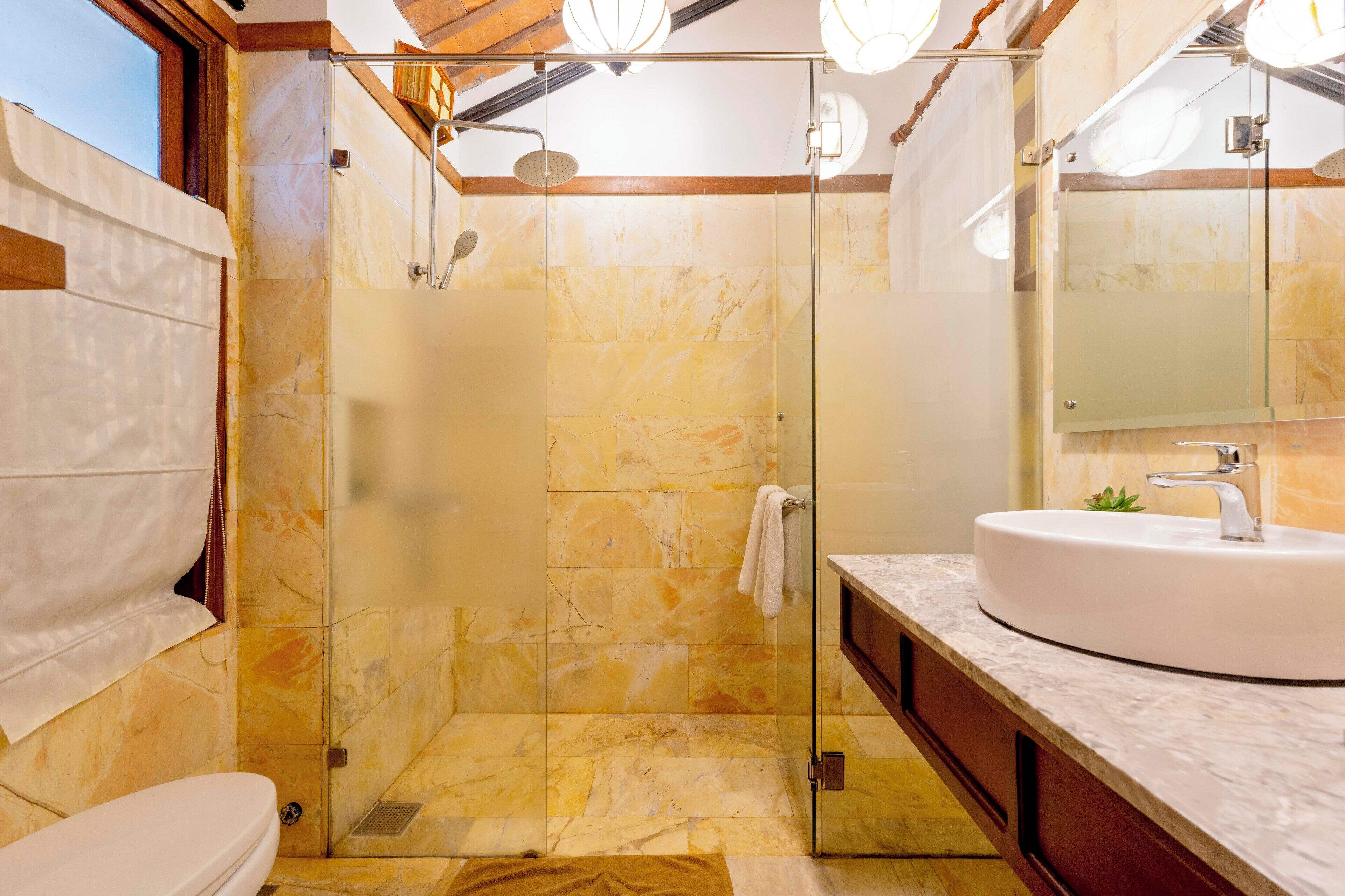 A modern bathroom with a glass-enclosed shower, a white sink, and a large mirror.