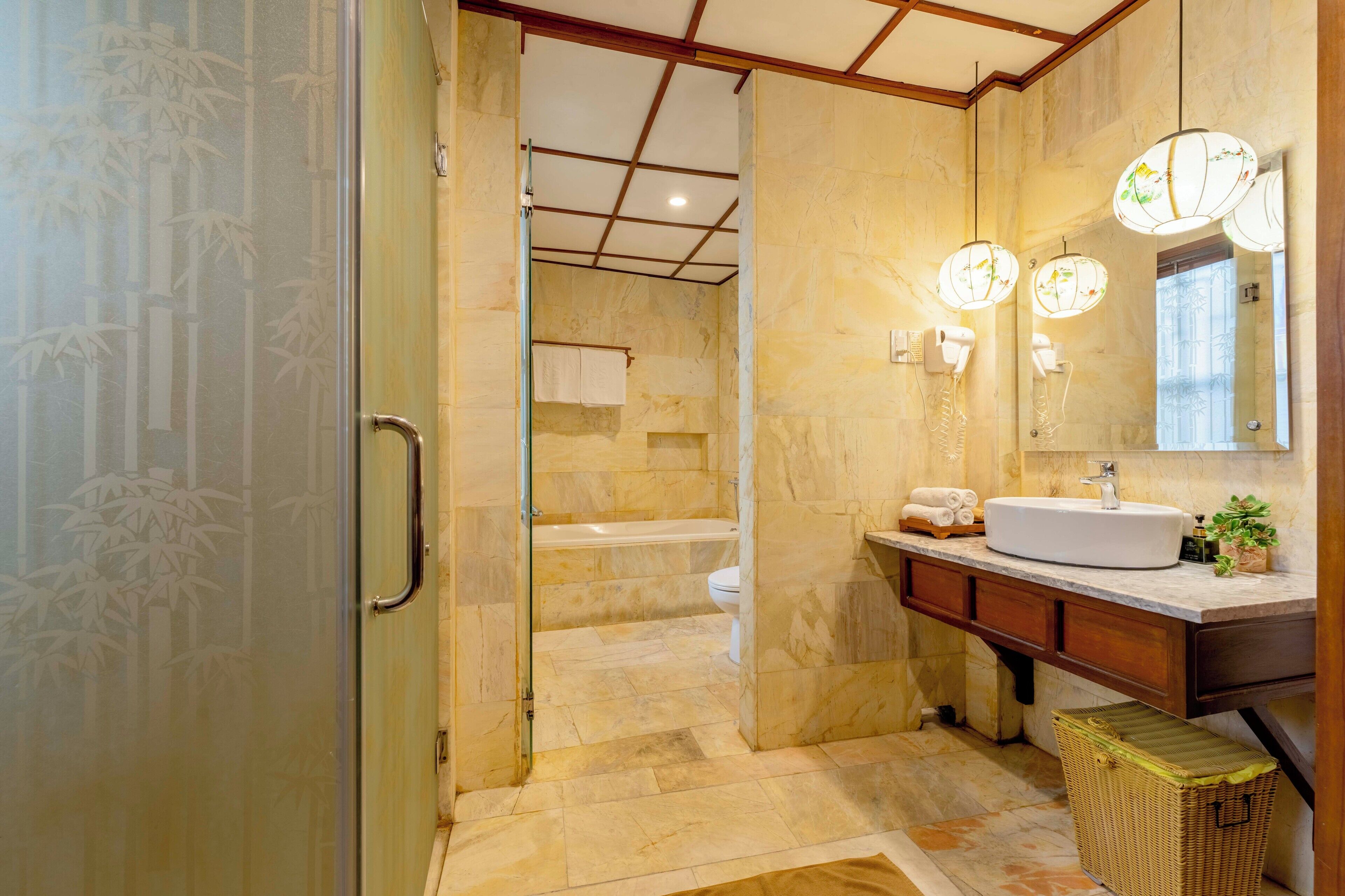 A bathroom with a glass door, a sink, a mirror, and a shower area.