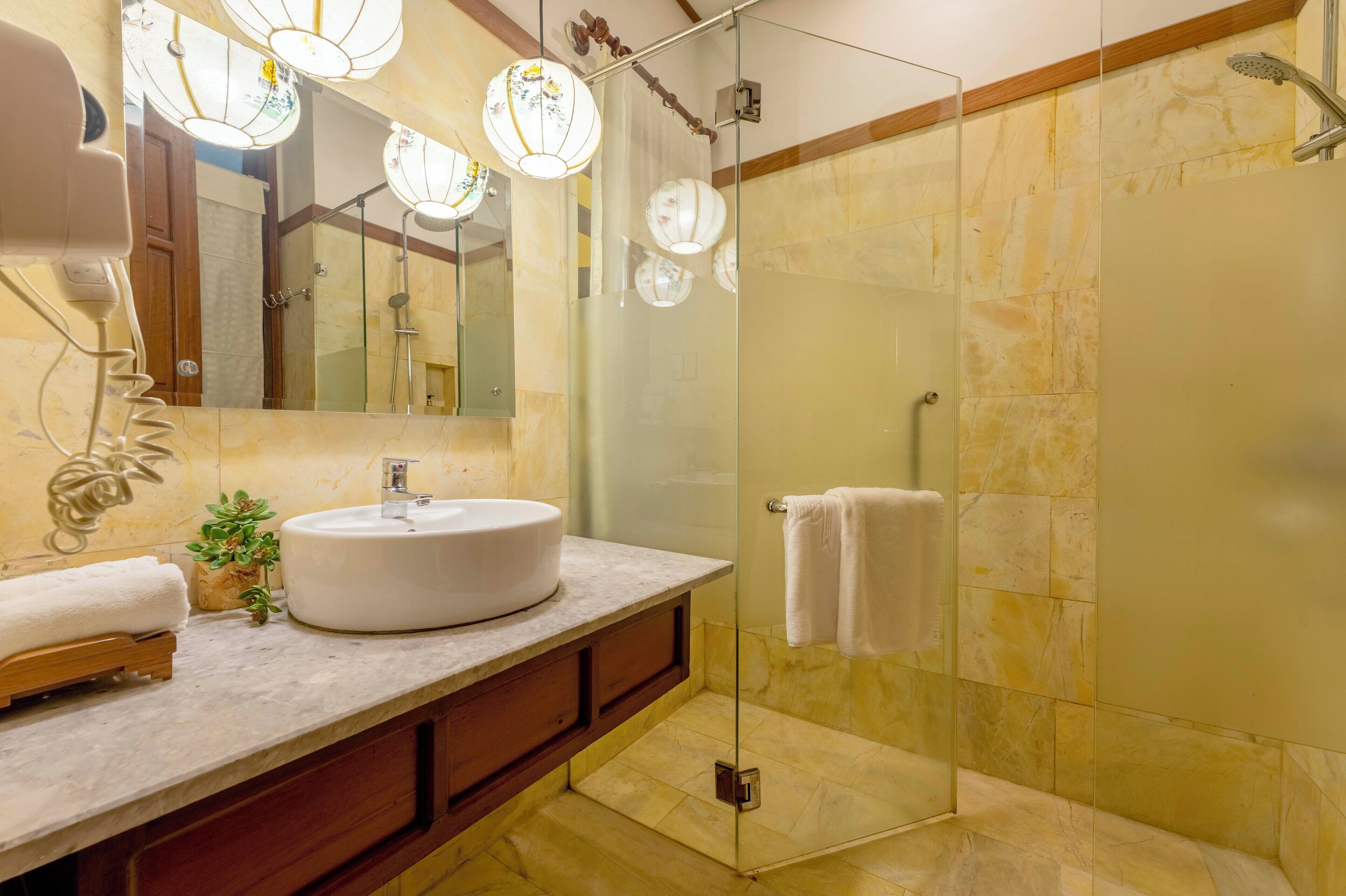 A modern bathroom with a glass-enclosed shower, a round sink, and a wooden vanity.