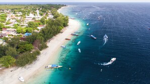 A coastal town with a beach, boats, and a prominent white building. - Bale Sampan Bungalows (Gili Trawangan)