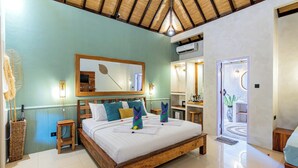 A bedroom with a wooden bed, a mirror, a wall-mounted fan, and a door leading to a bathroom. - Bale Sampan Bungalows (Gili Trawangan)