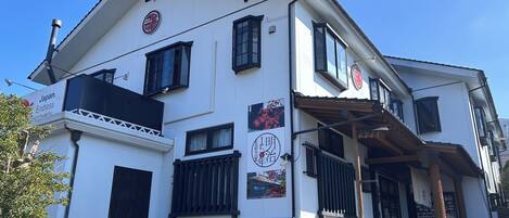 Un edificio japonés tradicional con fachada blanca, marcos de ventana negros y un balcón de madera.