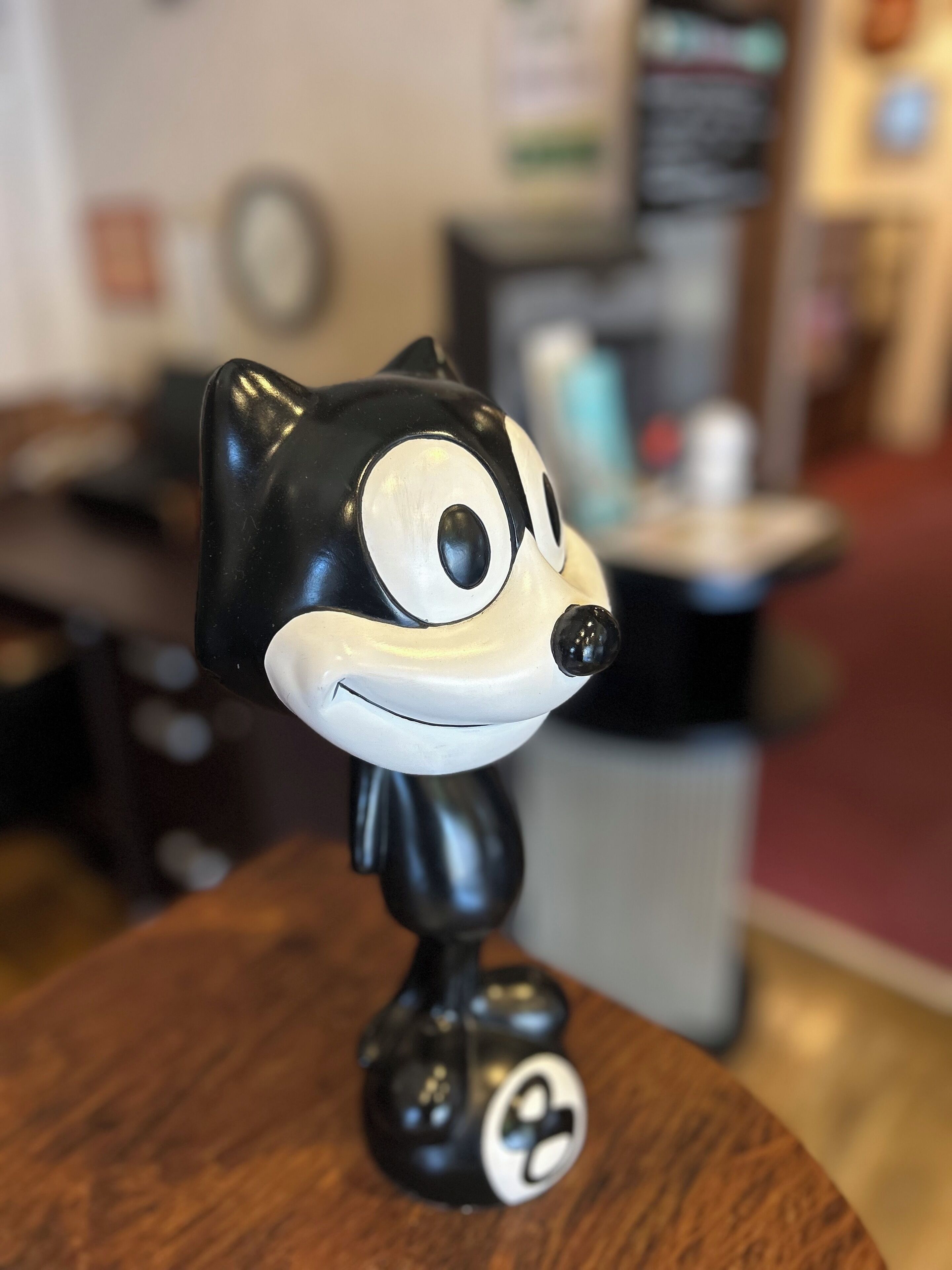 A figurine of a cat on a wooden surface.