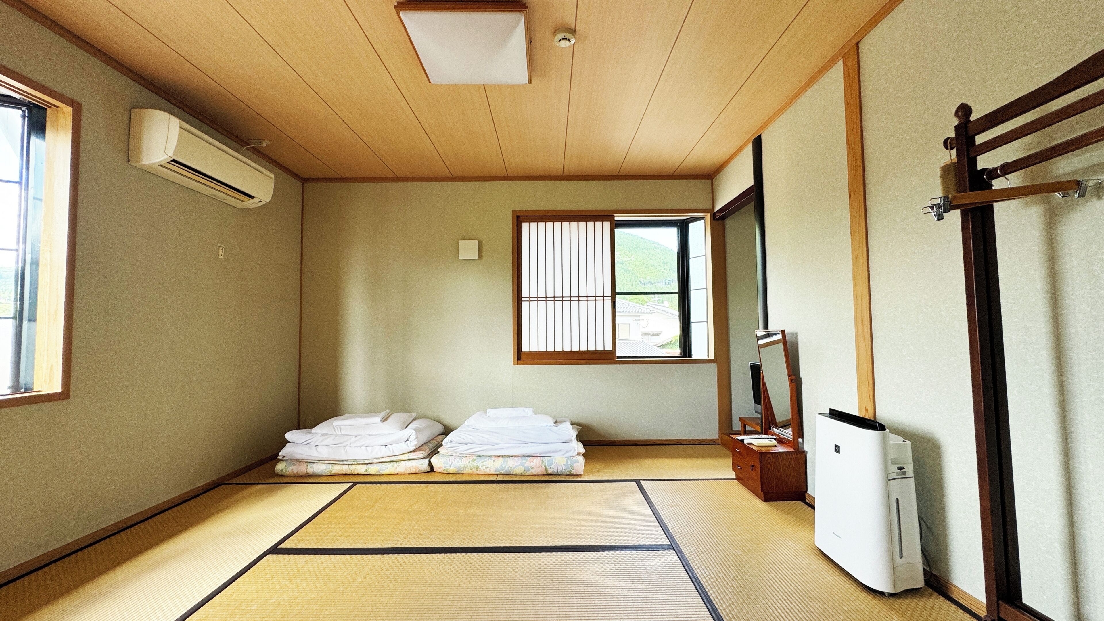 Una habitación tradicional japonesa con suelo de tatami, un futón, un shoji y un calentador, junto con un armario de madera.