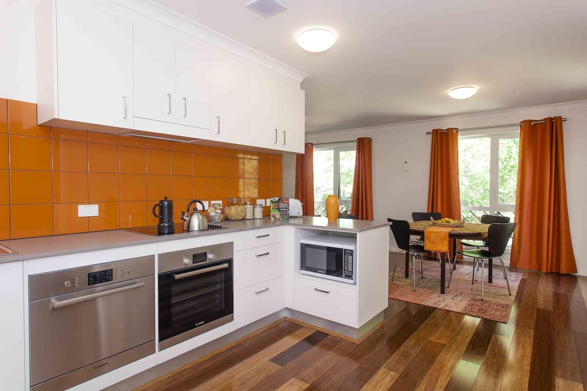 A modern kitchen with white cabinets, a built-in oven, and a microwave.