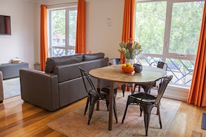 Ein modernes Wohnzimmer mit einem grauen Sofa, einem Holzesstisch und schwarzen Stühlen.