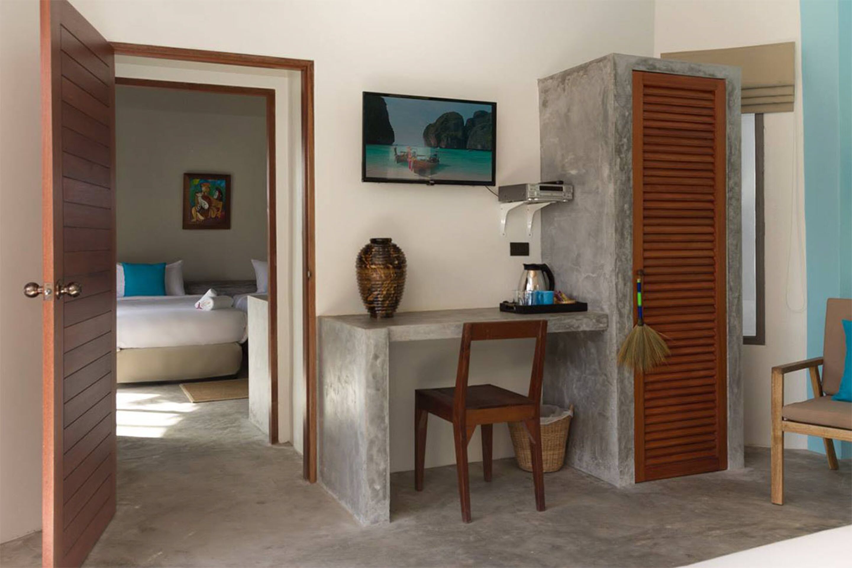 A room with a bed, a desk, a chair, a television, and a view of the sea.