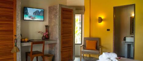 A hotel room with a bed, a desk with a chair, a TV, and a bathroom with a mirror.