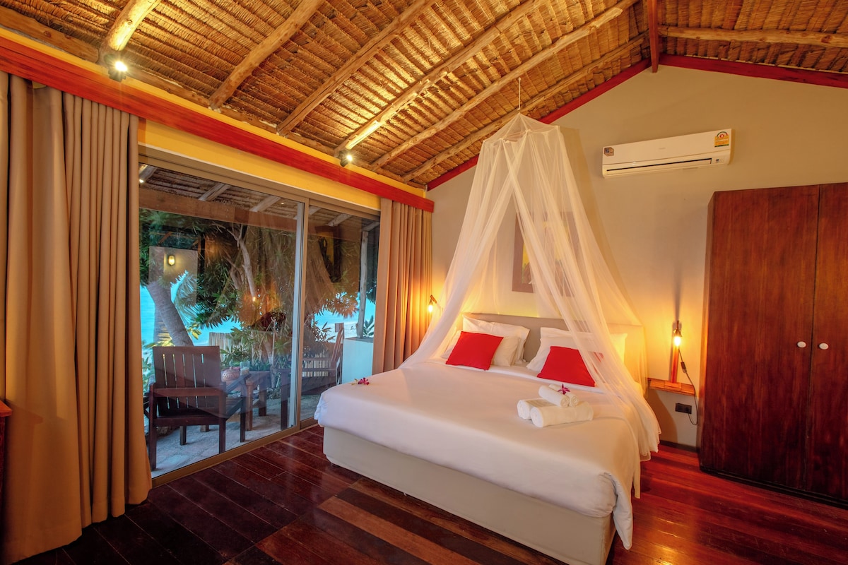 A bedroom with a bed, a nightstand, a wardrobe, and a glass door leading to an outdoor area.