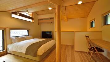 A bedroom with a bed, a desk, and a chair. There is a TV on a stand and a window with blinds.