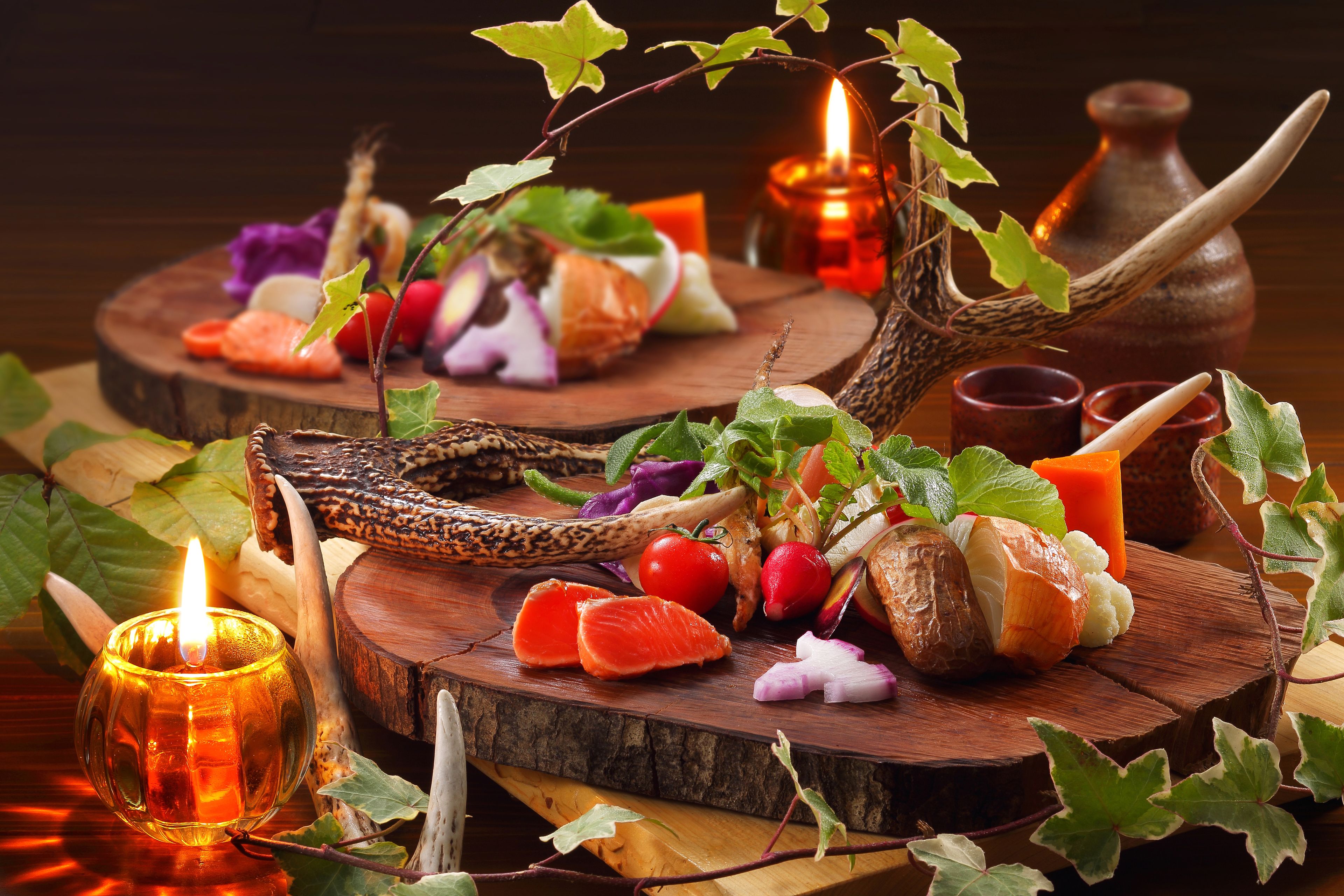 A wooden table with food items, a lit candle, and a vase.