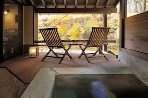 A wooden deck with two chairs facing a stone hot tub, a lantern, and a view of autumn foliage. - Syoubun (Minakami)