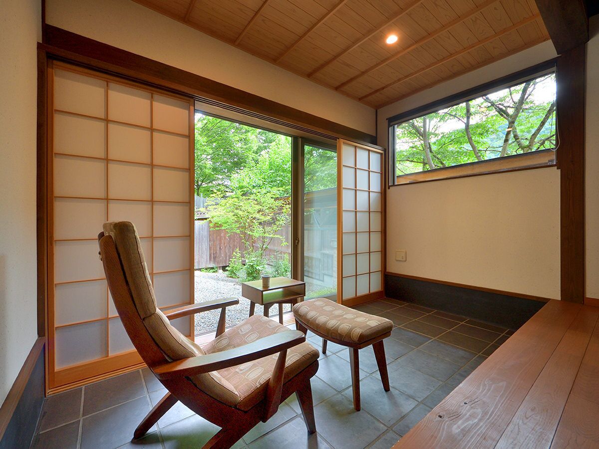 A traditional Japanese room with tatami flooring, a low table, and a cushioned chair.