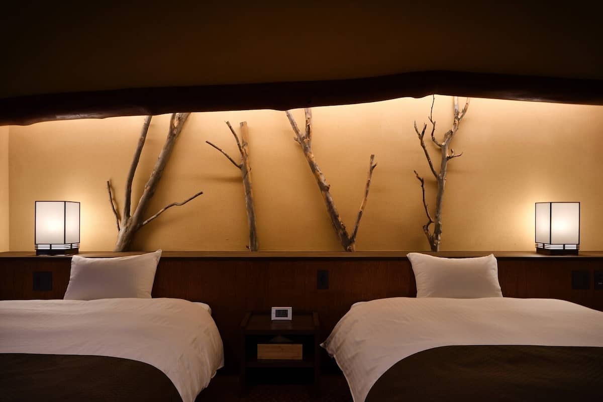 A hotel room with two beds, a wall-mounted clock, and two bedside lamps.