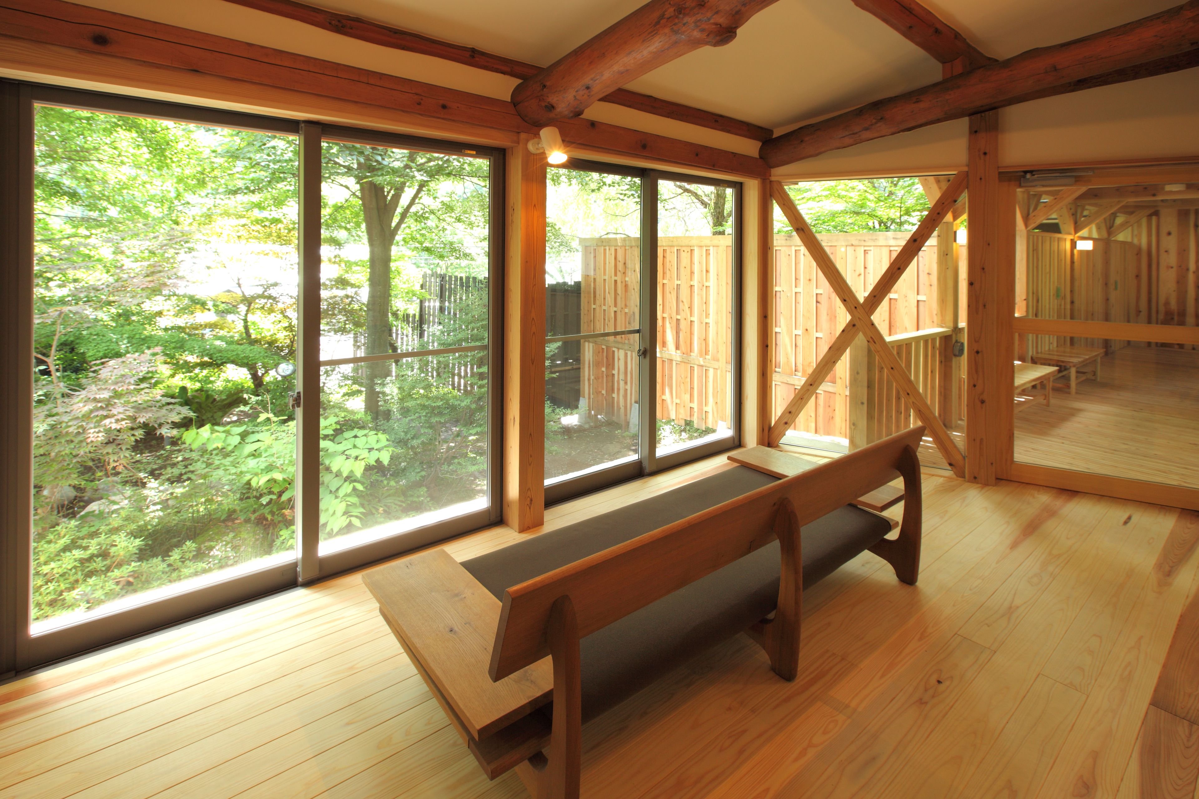 Un intérieur en bois, avec de grandes fenêtres, un banc et un plancher en bois.