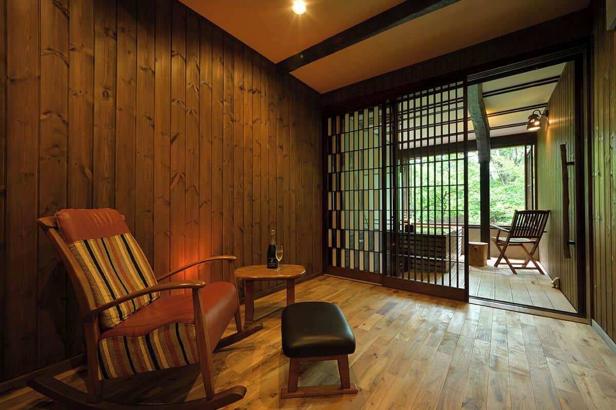 A wooden interior with a rocking chair, a small table, and a bench.