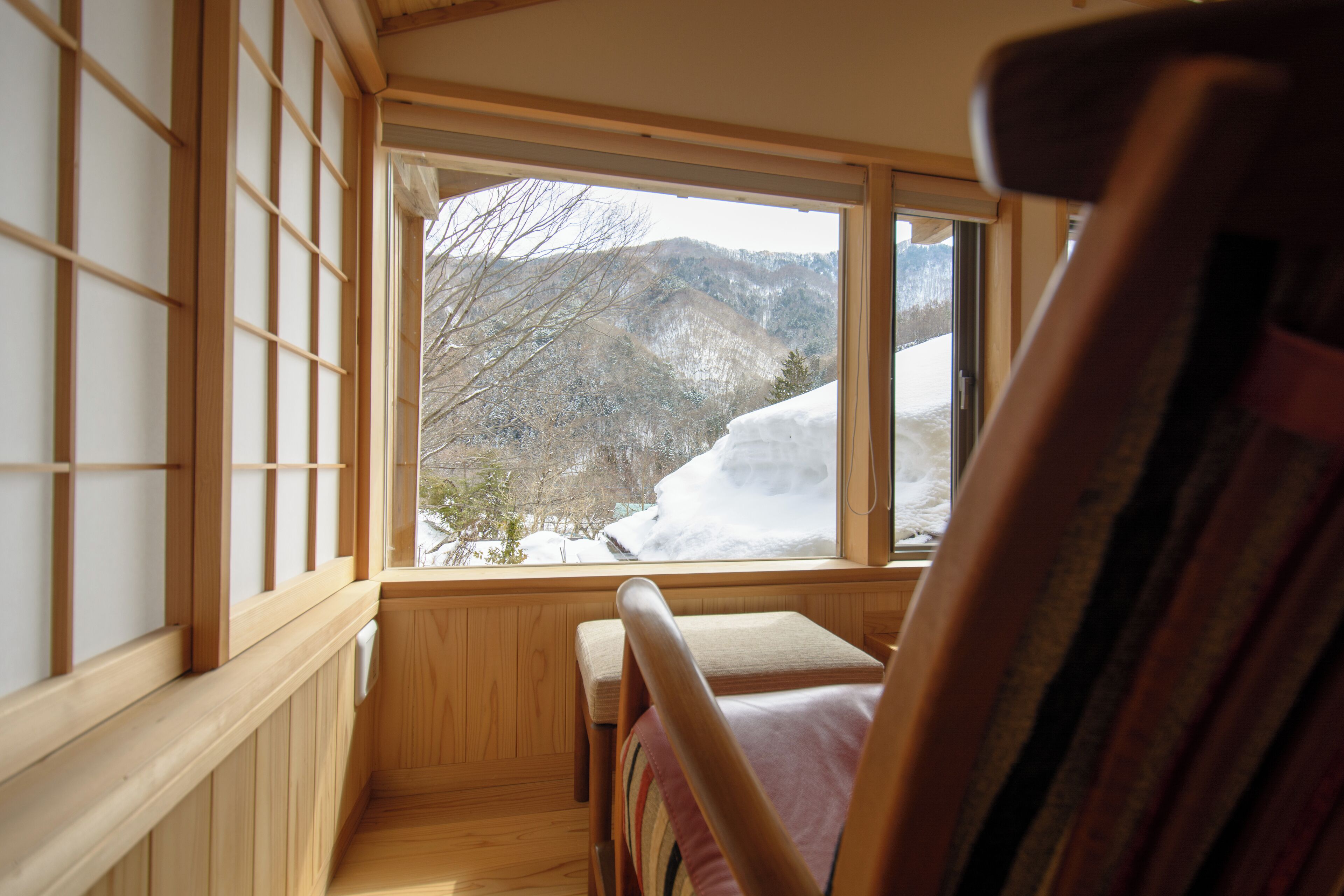 A wooden interior with a view of snow-covered mountains through a window.