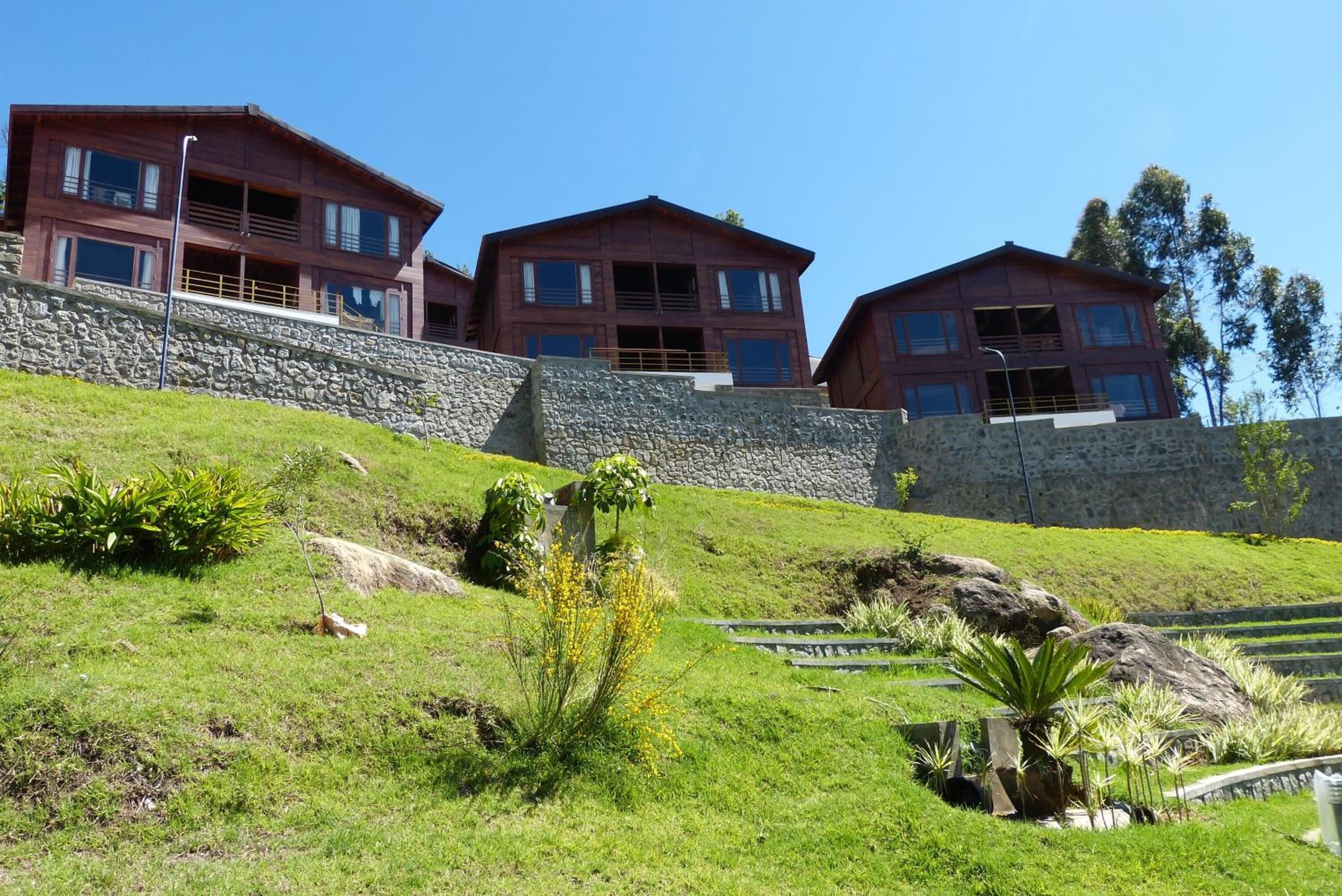 A hillside property with three multi-story buildings, stone retaining walls, and landscaped gardens.