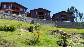 A hillside property with three multi-story buildings, stone retaining walls, and landscaped gardens.