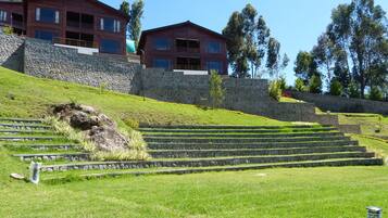 A multi-story building with a stone retaining wall and a grassy slope leading up to it.