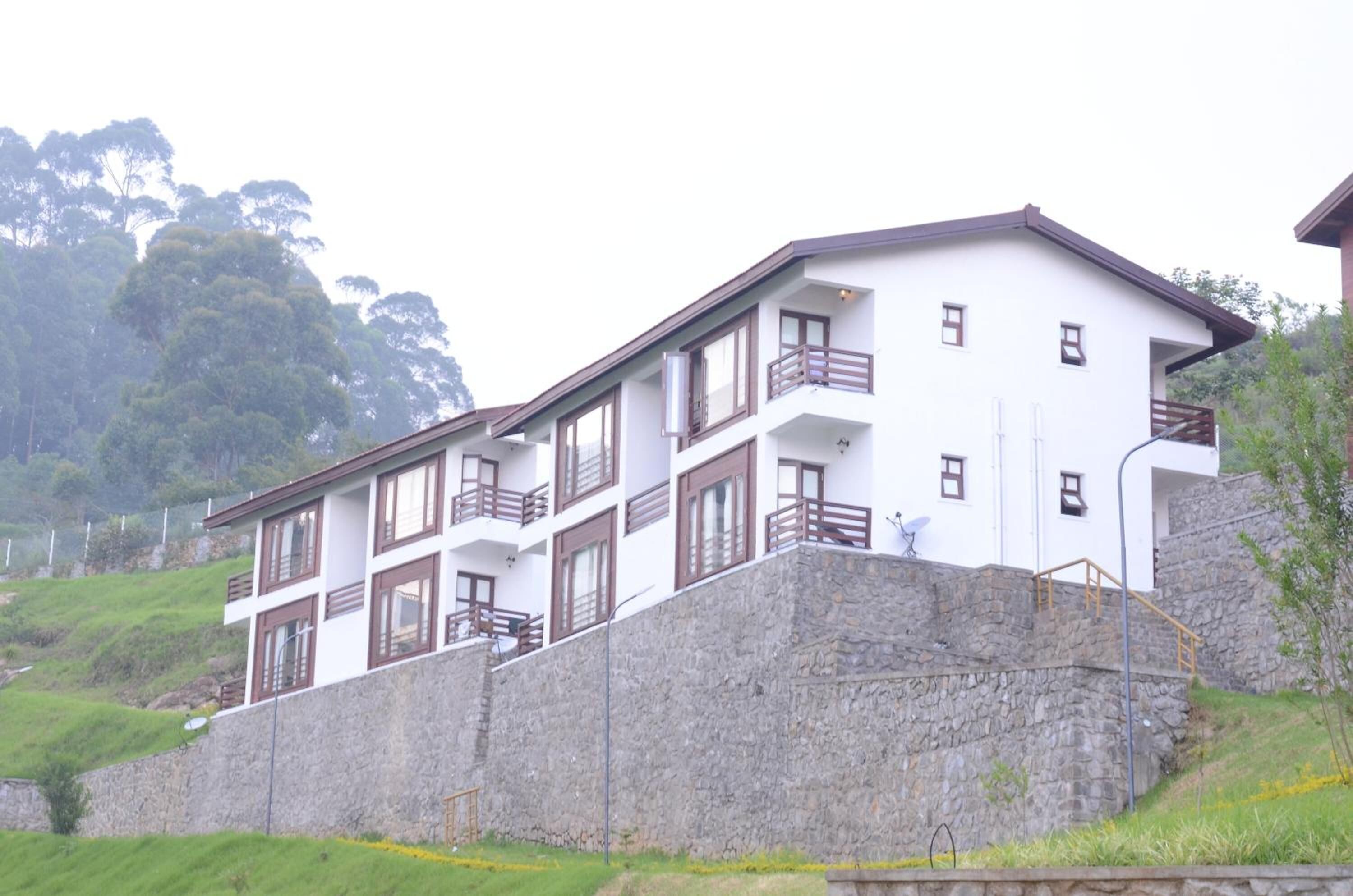 Un edificio de varios pisos con balcones, ubicado en una ladera con un muro de contención de piedra.