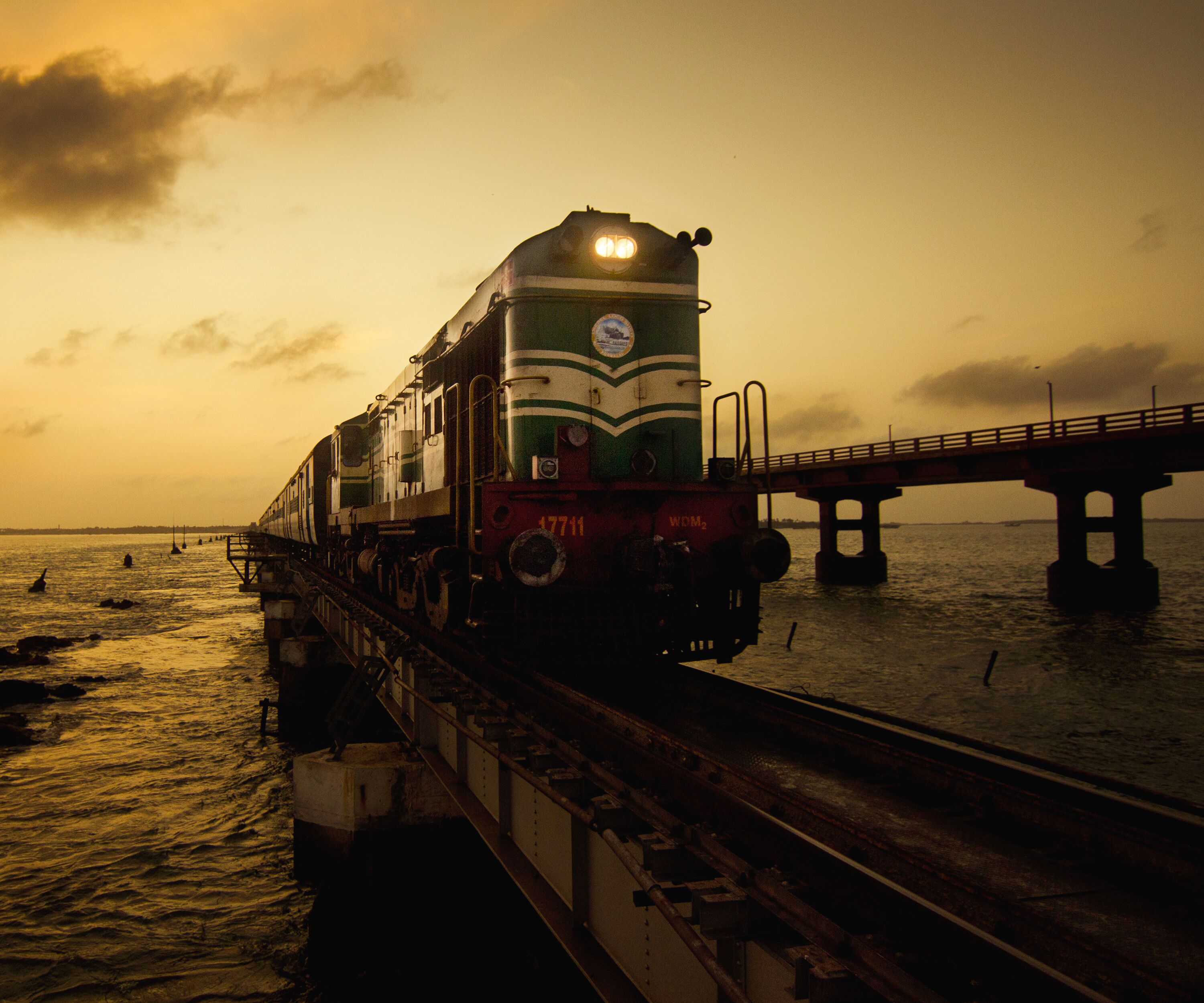 A train on a bridge over water during sunset.