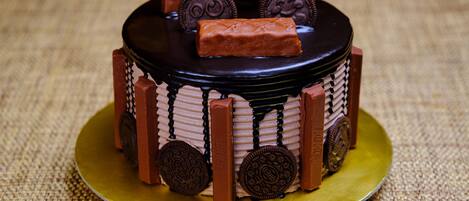 A small, round cake with chocolate decorations and Oreo cookies on a golden plate.