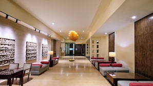 A modern hotel lobby with a long reception desk, seating areas, and decorative wall art. - Daiwik Hotels Rameswaram (Rameshwaram)