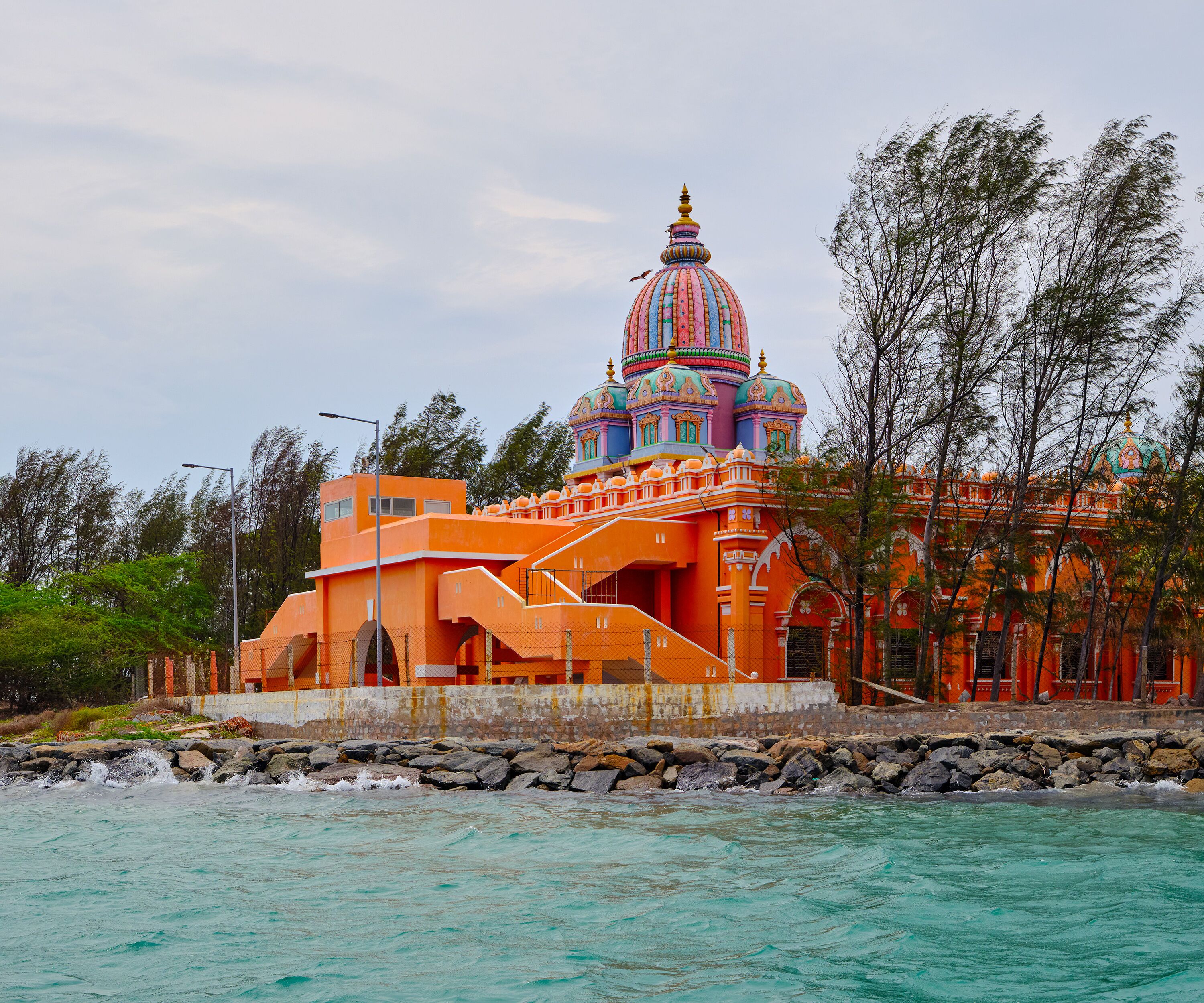 A colorful building with a prominent dome, situated by a rocky shoreline.