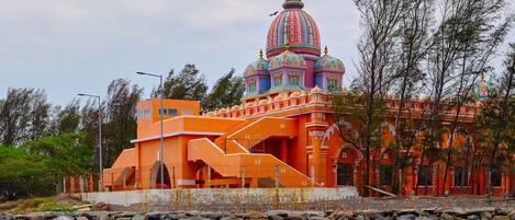 A colorful building with a prominent dome, situated by a rocky shoreline.