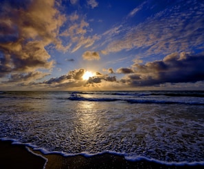 A beach with waves and a sunset. - Daiwik Hotels Rameswaram (Rameshwaram)