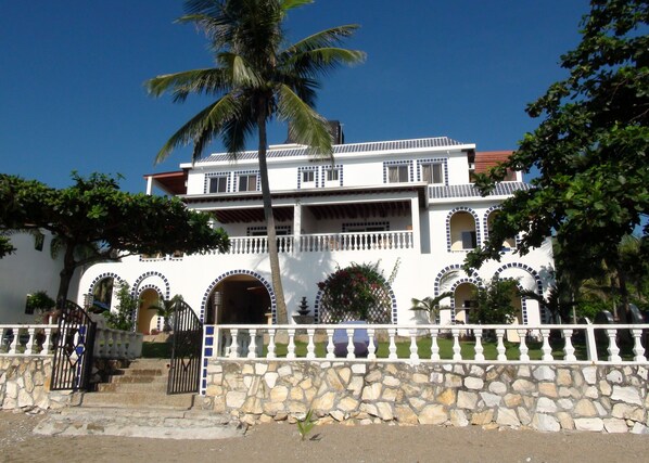 A two-story building with a stone facade, multiple balconies, and arched windows. - Squares Cafe and Apartments (Puerto Galera)