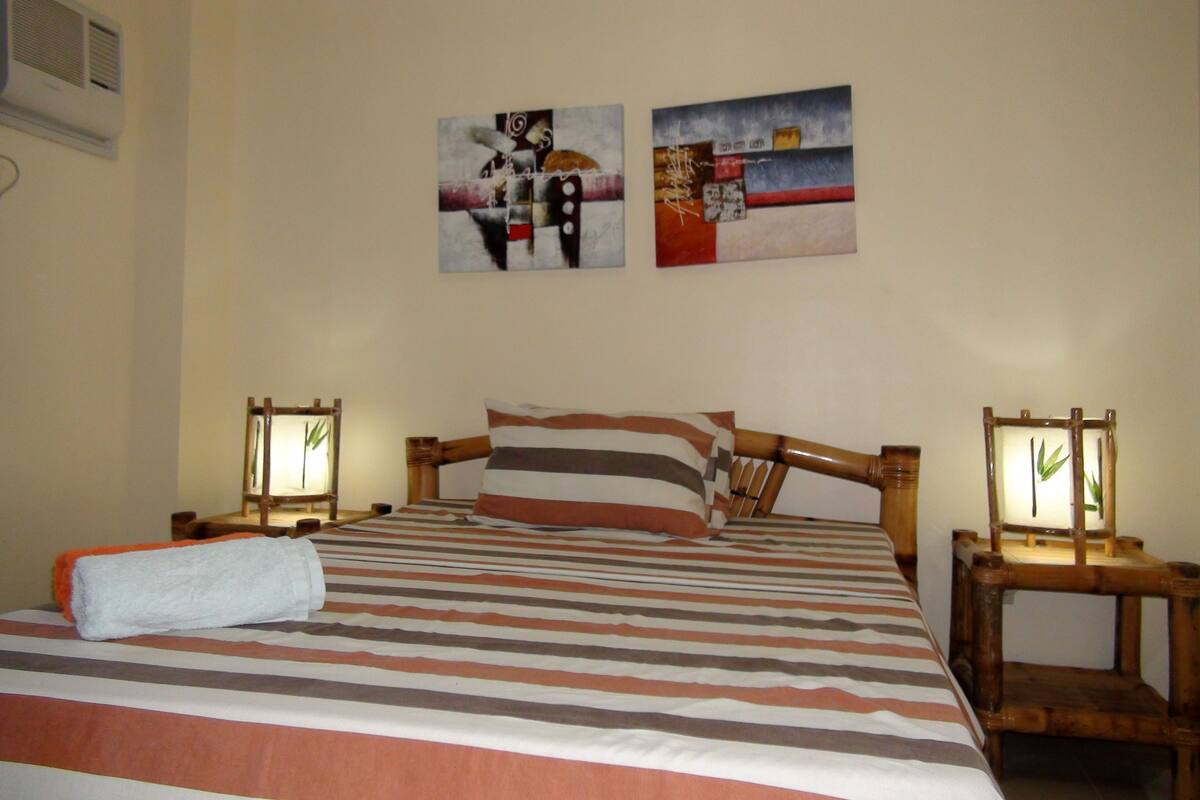 Ein Hotelzimmer mit einem Bett, zwei Bildern an der Wand und zwei Nachttischen mit Lampen.