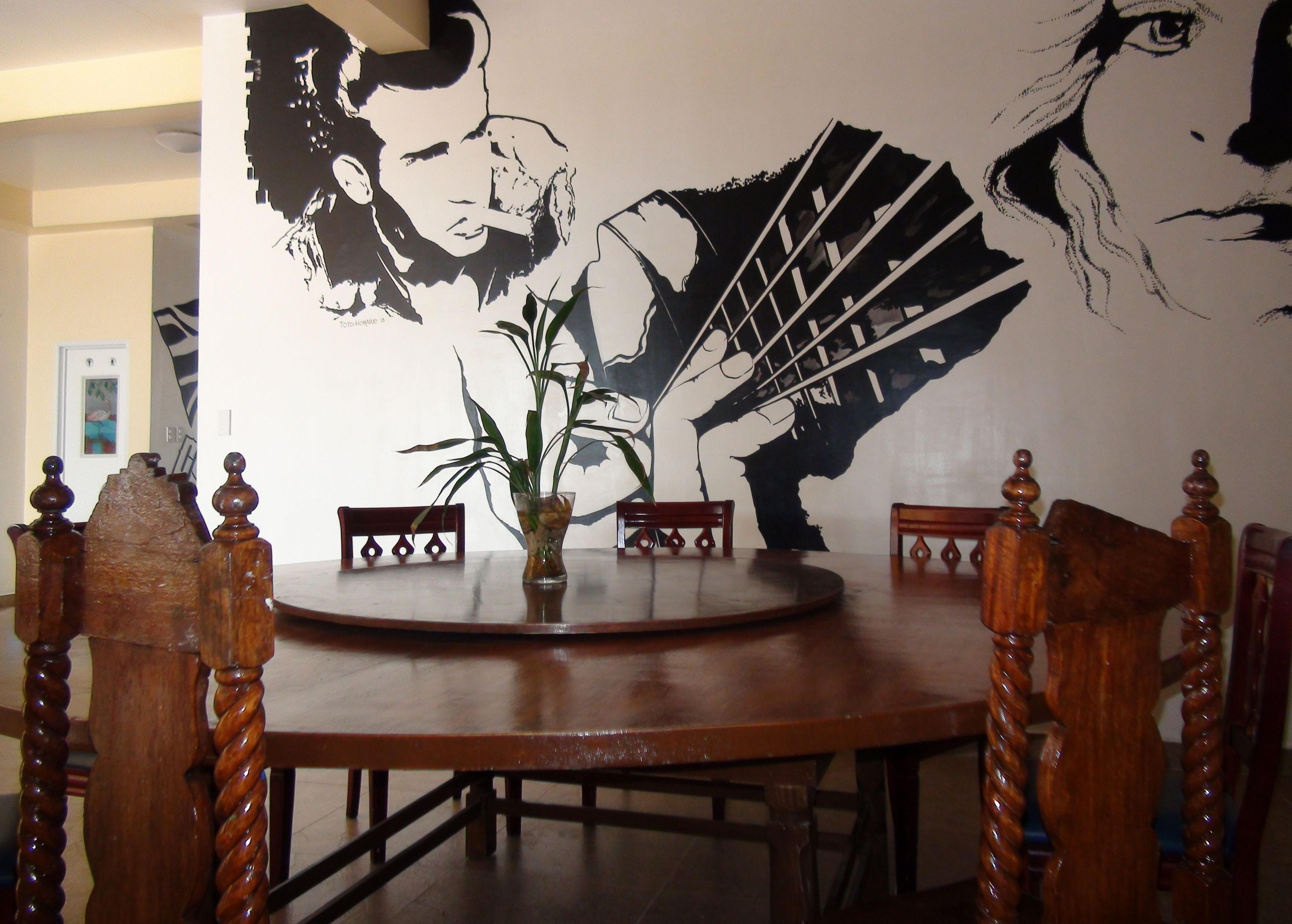 A dining area with a round wooden table, four wooden chairs, and a large wall mural.